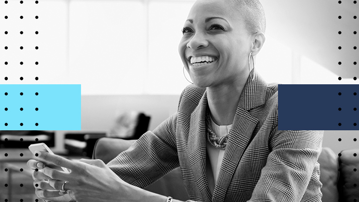 a smiling woman in a business suit looks up from her phone