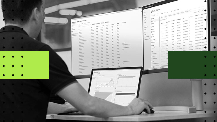 A person working at a desk with three computer screens