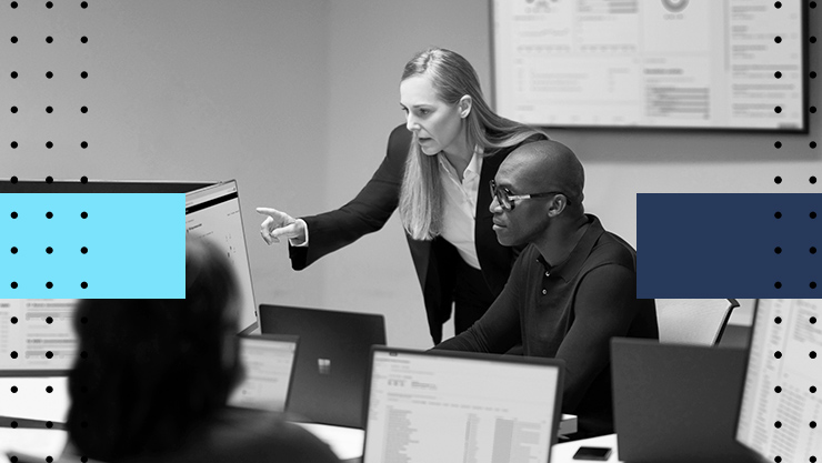 A woman and a man looking at computer monitor in an office setting