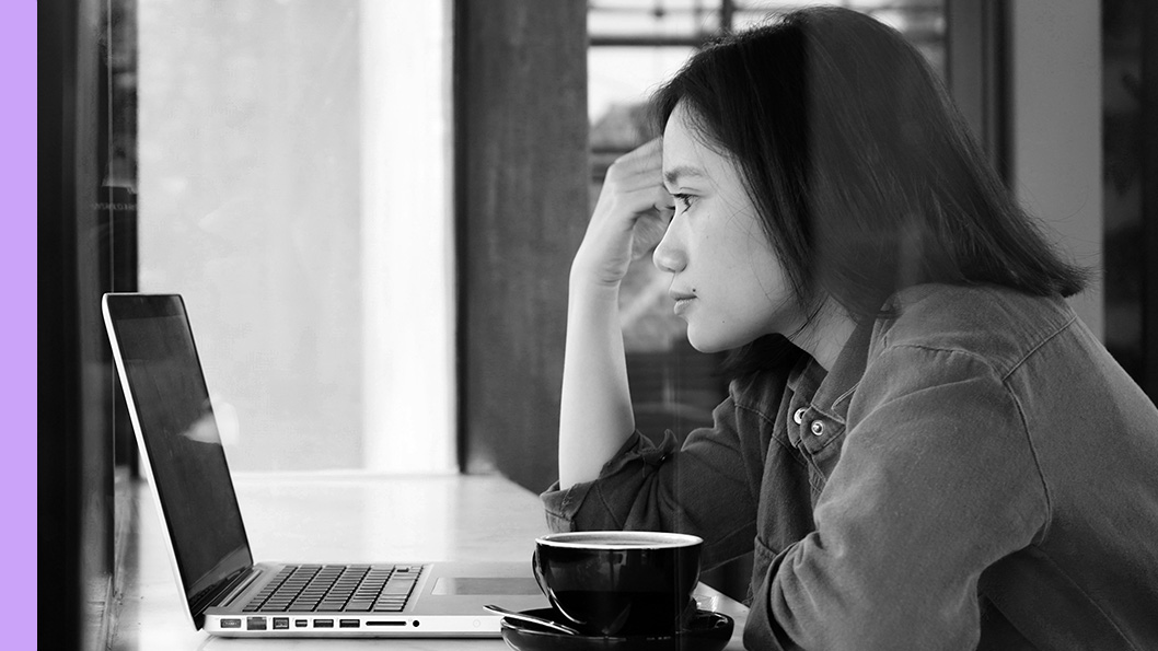 A woman sits at a table working on a laptop